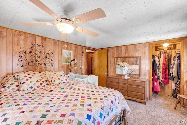 carpeted bedroom with a spacious closet, ceiling fan, a closet, and wood walls