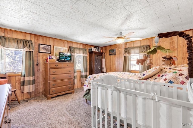 carpeted bedroom with ceiling fan and wooden walls