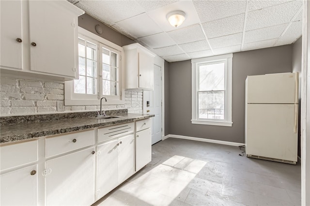 kitchen with white cabinets, a drop ceiling, sink, and white fridge