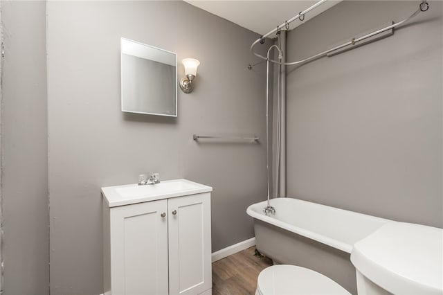 bathroom with hardwood / wood-style flooring, a bathtub, vanity, and toilet