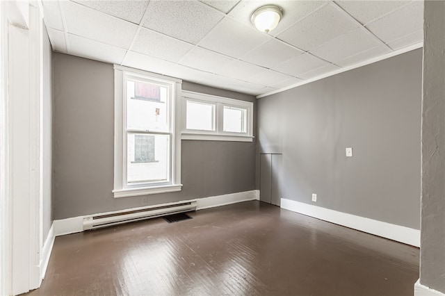 empty room with a baseboard radiator, dark hardwood / wood-style flooring, crown molding, and a paneled ceiling