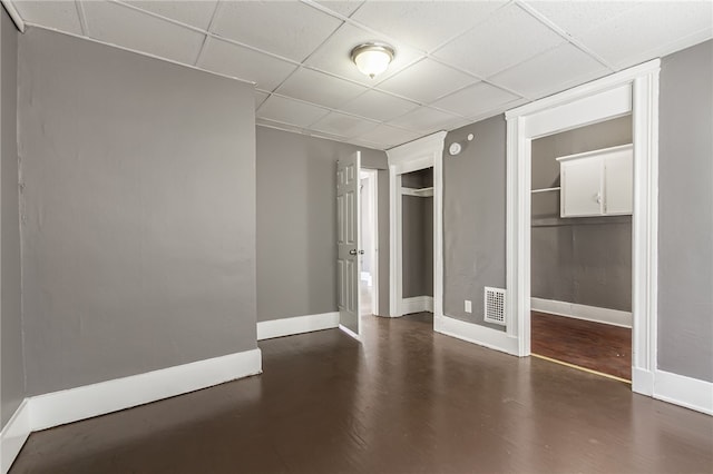 unfurnished bedroom featuring dark hardwood / wood-style flooring, a paneled ceiling, and a closet