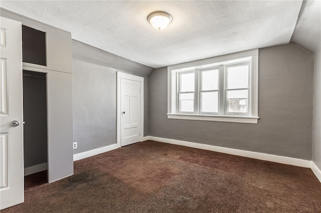 unfurnished bedroom featuring dark colored carpet and lofted ceiling