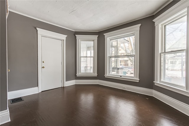 spare room featuring dark hardwood / wood-style flooring, ornamental molding, and a healthy amount of sunlight