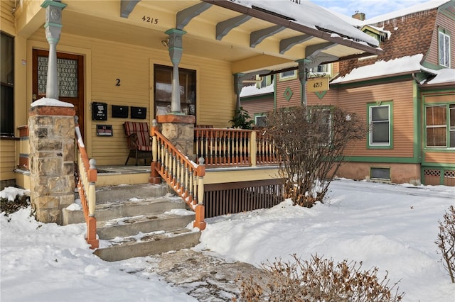 snow covered property entrance with a porch