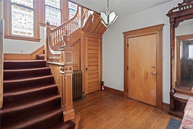 stairs featuring a chandelier, wood-type flooring, and radiator heating unit