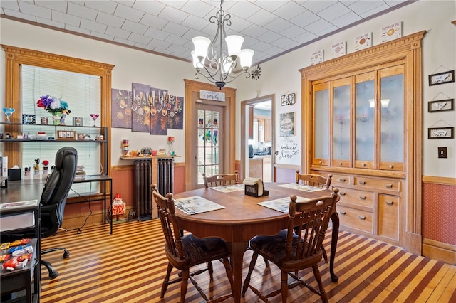 carpeted dining area with radiator, ornamental molding, and a notable chandelier