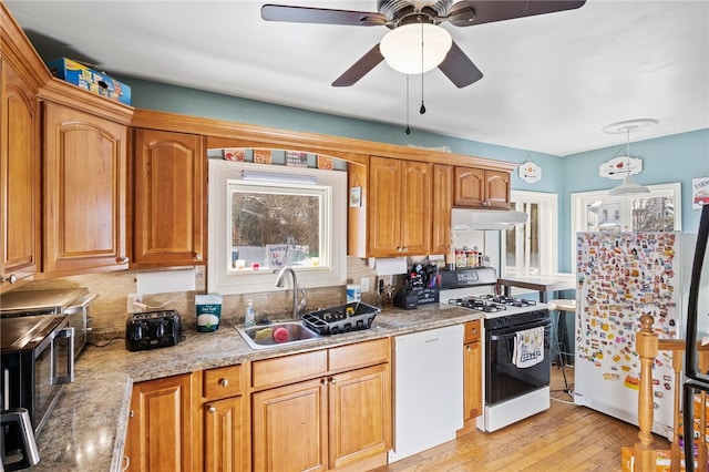 kitchen with dishwasher, hanging light fixtures, gas range oven, light hardwood / wood-style flooring, and sink