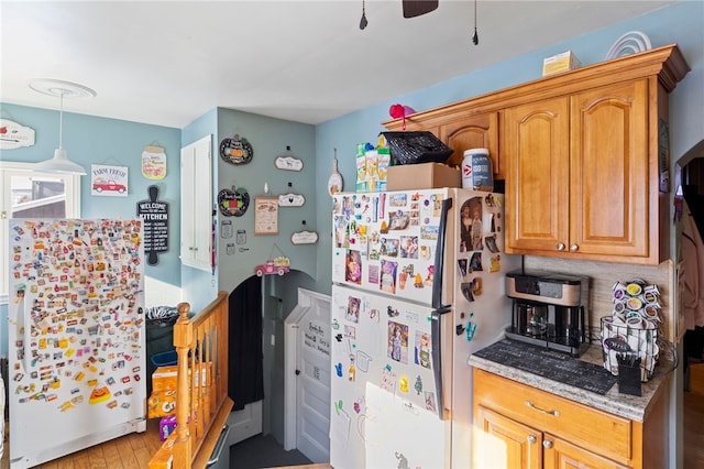 kitchen featuring light stone counters, refrigerator, white fridge, and light wood-type flooring