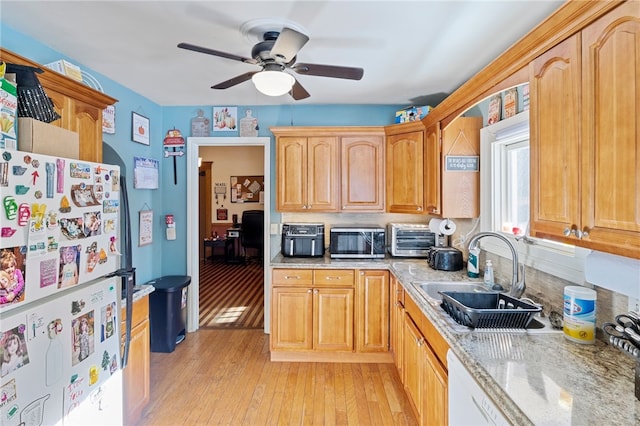 kitchen featuring white fridge, ceiling fan, light wood-type flooring, light stone countertops, and sink