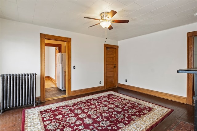 spare room featuring ceiling fan, dark hardwood / wood-style floors, and radiator heating unit