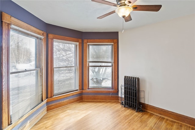 spare room with light wood-type flooring, ceiling fan, and radiator heating unit