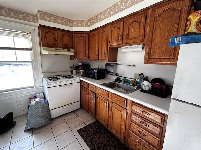 kitchen featuring white gas range, light tile patterned floors, and sink