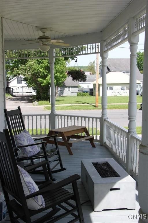 wooden deck with a porch, a fire pit, and ceiling fan