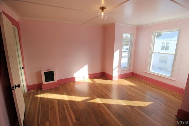 spare room with crown molding, light wood-type flooring, and heating unit