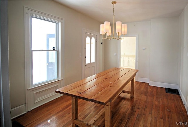 dining area with dark hardwood / wood-style flooring and an inviting chandelier