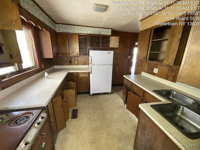 kitchen with sink, wood walls, white fridge, and cooktop