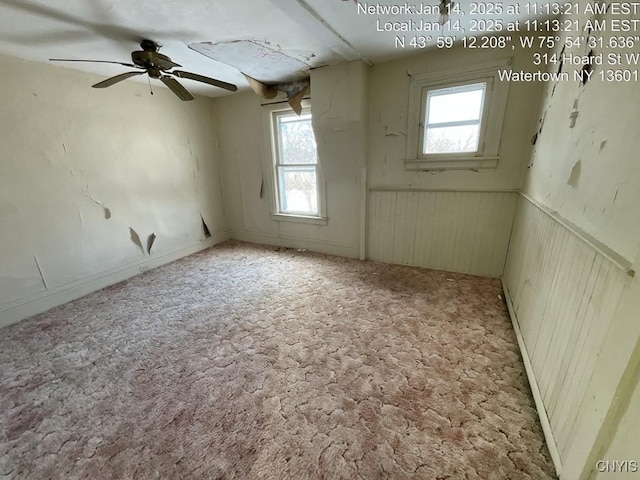 carpeted empty room with ceiling fan and plenty of natural light