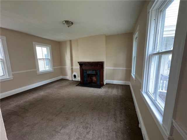 unfurnished living room featuring a fireplace and dark colored carpet