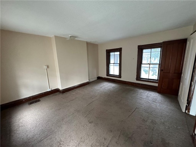 empty room with a textured ceiling and dark colored carpet