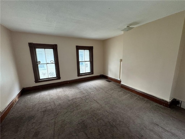 empty room featuring dark carpet and a textured ceiling