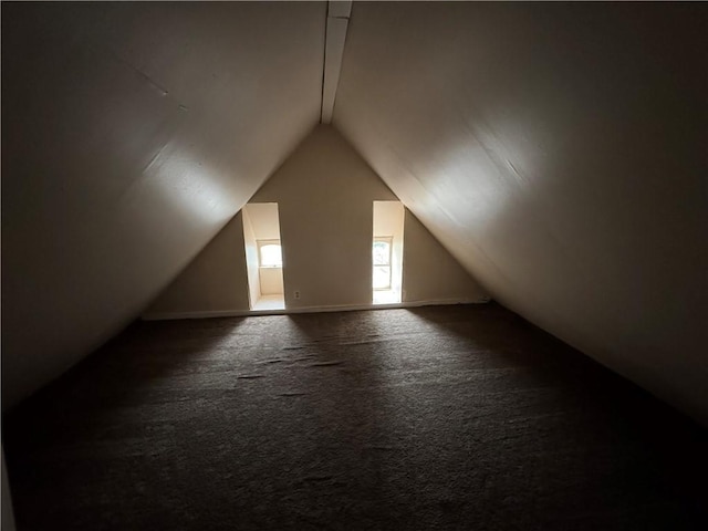 bonus room with dark colored carpet and vaulted ceiling