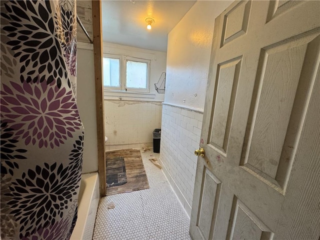 bathroom with a tub to relax in and tile walls