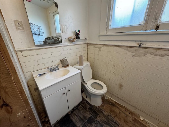 bathroom featuring vanity, toilet, a healthy amount of sunlight, and tile walls