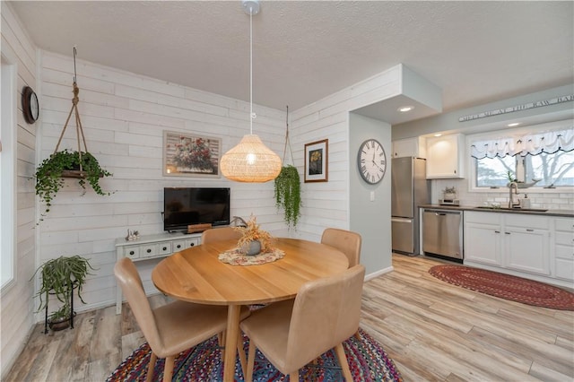 dining space featuring sink, light hardwood / wood-style flooring, and a textured ceiling