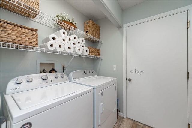 clothes washing area with washer and clothes dryer and light hardwood / wood-style flooring