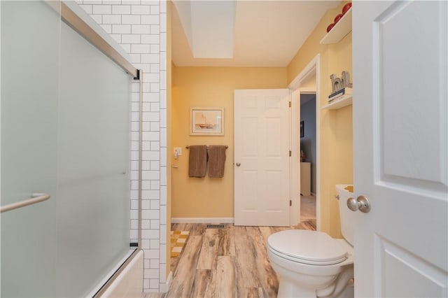 bathroom featuring shower / bath combination with glass door, toilet, and wood-type flooring