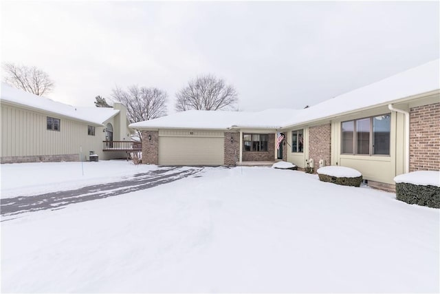 snow covered back of property featuring a garage