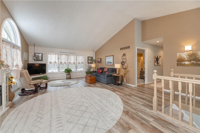 living room featuring light wood-type flooring and high vaulted ceiling