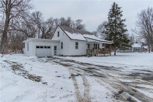 view of snowy exterior featuring a porch and a garage