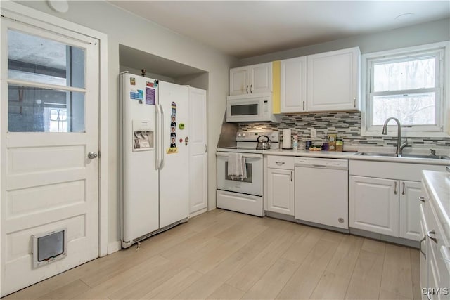 kitchen featuring sink, light wood-type flooring, white cabinetry, tasteful backsplash, and white appliances