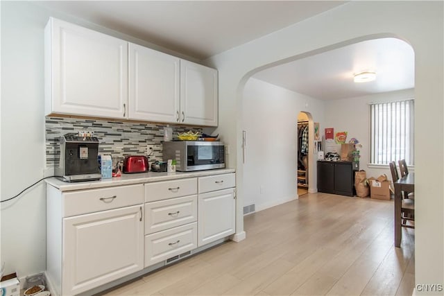 kitchen with backsplash, white cabinetry, and light wood-type flooring