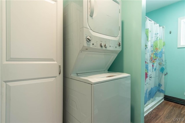 washroom with stacked washer / drying machine and dark hardwood / wood-style flooring