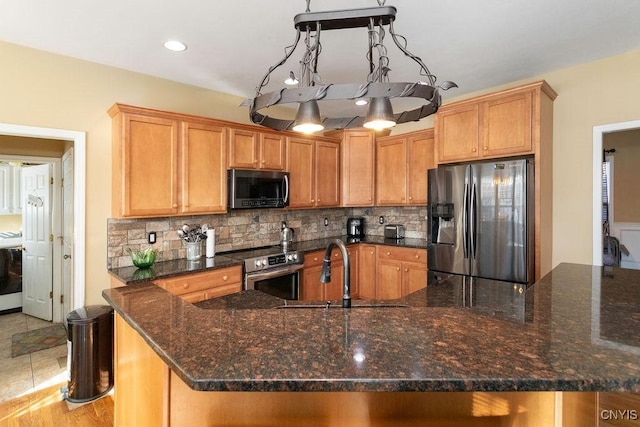 kitchen featuring sink, backsplash, stainless steel appliances, and dark stone countertops