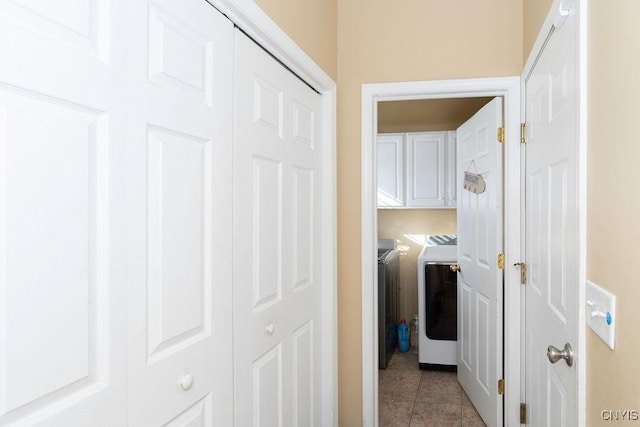 laundry room with washer and clothes dryer, light tile patterned floors, and cabinets