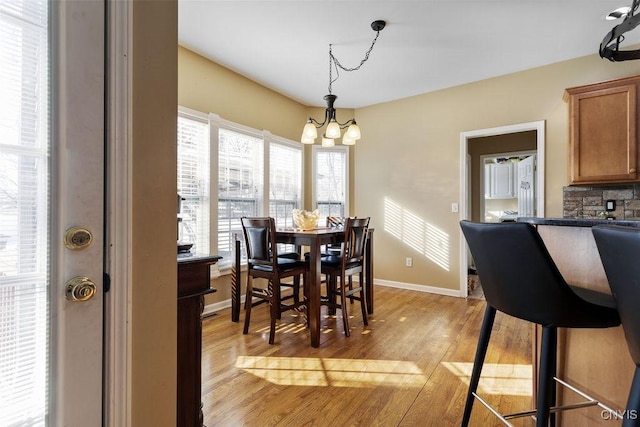 dining space with light wood-type flooring and an inviting chandelier