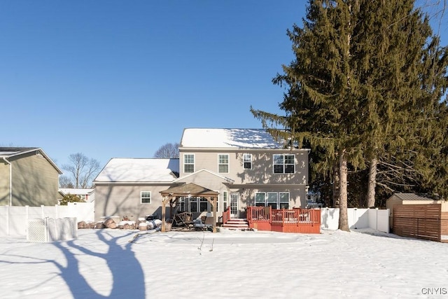 snow covered back of property with a gazebo and a wooden deck