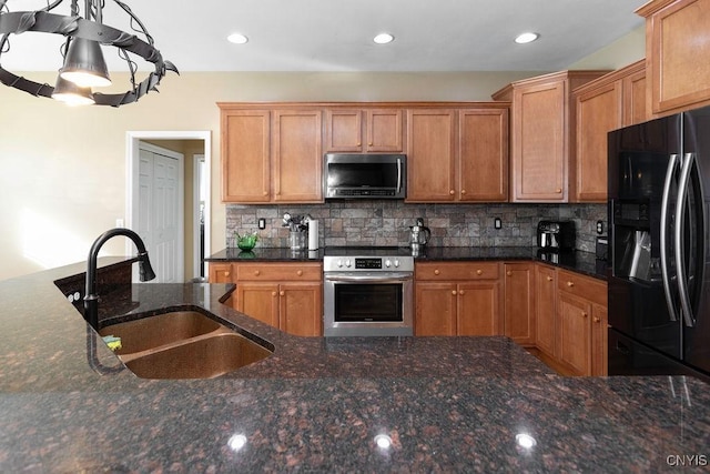 kitchen with sink, backsplash, dark stone countertops, and appliances with stainless steel finishes