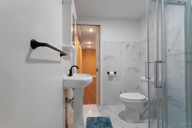 bathroom with toilet, tile walls, and a shower with shower door