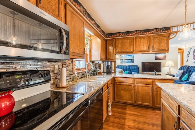 kitchen featuring hanging light fixtures, dark hardwood / wood-style flooring, sink, light stone counters, and black appliances