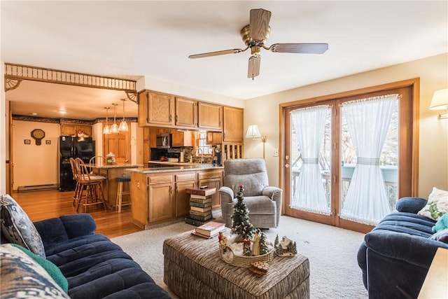 living room with ceiling fan, light hardwood / wood-style floors, and a baseboard heating unit