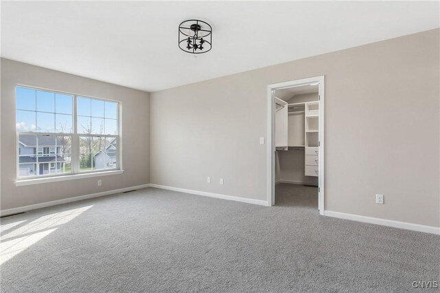 unfurnished bedroom with a closet, a walk in closet, and carpet flooring