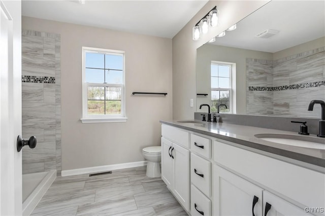 bathroom with toilet, vanity, and a tile shower