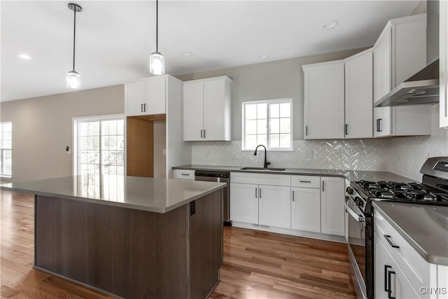 kitchen with pendant lighting, white cabinets, a kitchen island, wall chimney range hood, and stainless steel appliances