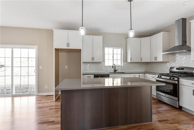 kitchen featuring gas range, white cabinets, wall chimney exhaust hood, and a kitchen island