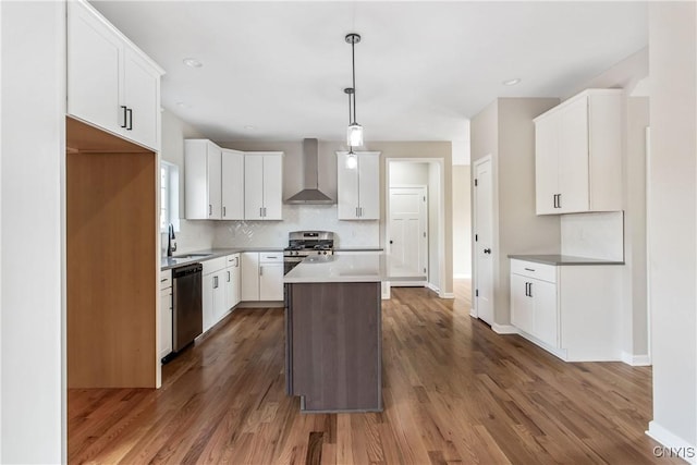 kitchen with wall chimney range hood, a kitchen island, white cabinets, and pendant lighting